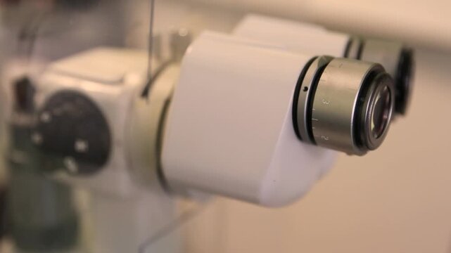 Close up video footage of a medical doctor eye positioned at the binocular eyepieces of a laboratory microscope. Scientific research process shown through precise focus adjustment and examination 