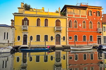 Old colourful houses and boats, reflection in canal of Chioggia, Italy