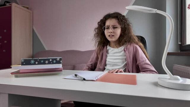 Schoolgirl frustrated while studying at desk, education stress and learning difficulties