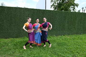 Three dancers in national costumes dance in the park on a summer day. Indian dance lessons, choreography.