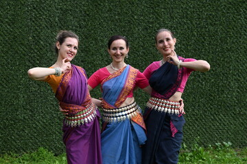 Three dancers in national costumes dance in the park on a summer day. Indian dance lessons, choreography.