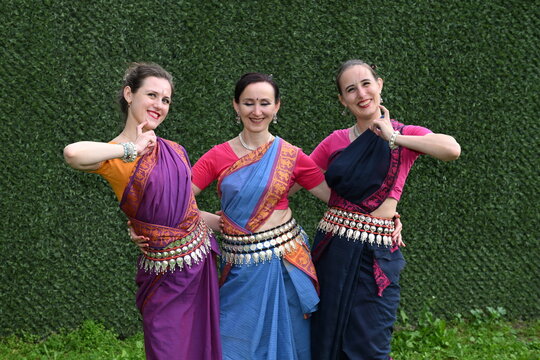 Three dancers in national costumes dance in the park on a summer day. Indian dance lessons, choreography.