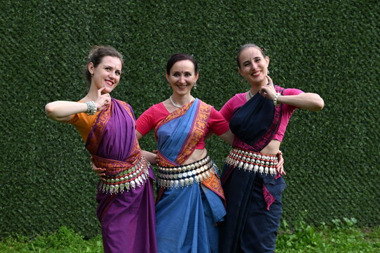 Three dancers in national costumes dance in the park on a summer day. Indian dance lessons, choreography.