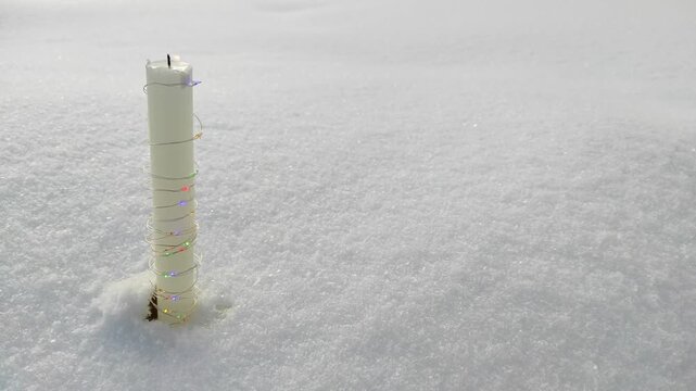 A candle burns in the snow