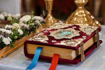 Ornate Religious Book with Silver Embellishments and Floral Arrangements on Church Altar in Warm Golden Light
