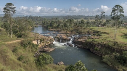 Fototapeta premium Scenic river flowing through lush landscape under a blue sky with clouds