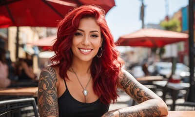 Young woman with vibrant red hair and tattoos smiles at a cafe in a bustling city street during the daytime