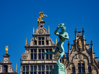 Fototapeta premium Brabo Fountain Grote Markt Antwerp Clear Sky - Wide-angle view of the Brabo Fountain and historic guildhalls on the Grote Markt (Great Market Square) in Antwerp, Belgium, under a clear blue sky.