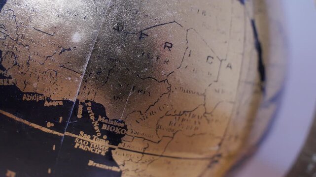 Vintage black and gold world globe on a desk with soft natural light and shallow depth of field. Elegant decorative globe symbolizing geography, travel, education, exploration, and global business.