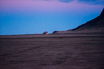 Obraz premium Cargo Truck Driving on a Remote Highway at Twilight Under a Purple Sky in Iceland