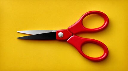 Open red plastic scissors positioned at a 35-degree angle on a bright yellow background, showcasing a clean top-down view with distinct blade lengths and a central pivot point