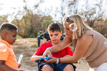 Caretaker helping boy with cerebral palsy blowing bubbles © Jordi Mora