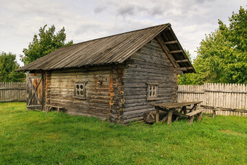Fototapeta premium Historic wooden cabin surrounded by grass and trees, symbolizing simplicity, nature connection, and old countryside life.
