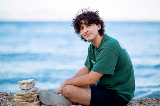 Young man relaxing by the sea with a rock stack