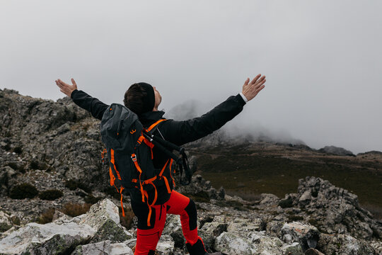 Hiker celebrating on cloudy mountain peak