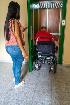 Man in wheelchair entering elevator with assistance