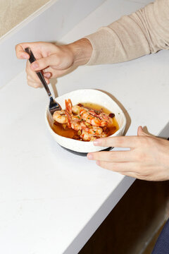 Person enjoying seafood dish with fork in kitchen