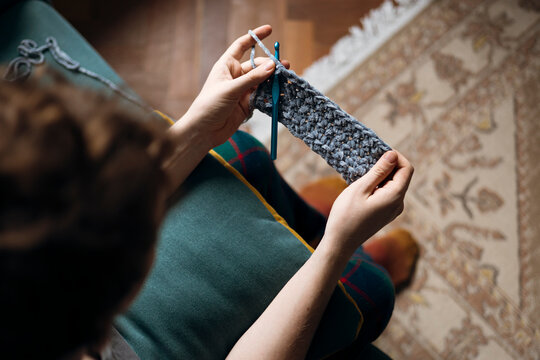 Person crocheting a textured piece in a cozy setting