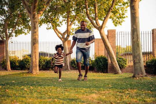 Father and daughter running joyfully in the park