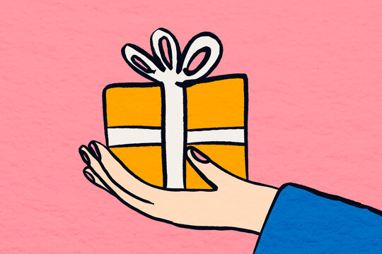 Hand holding a gift wrapped with ribbon on pink backdrop