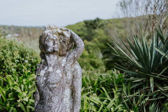 Weathered stone statue amidst lush garden