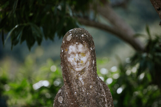 Weathered stone statue in a serene garden setting