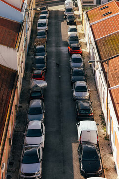 Urban street view with parked cars and textured roofs