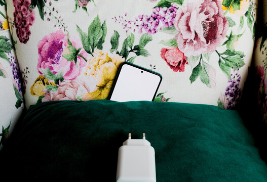 Smartphone peeking from pillow with charging adapter