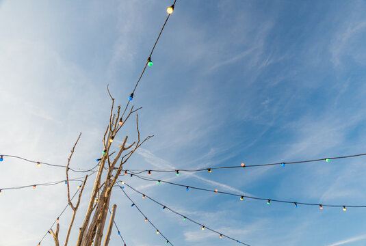 Colorful string lights against a bright blue sky