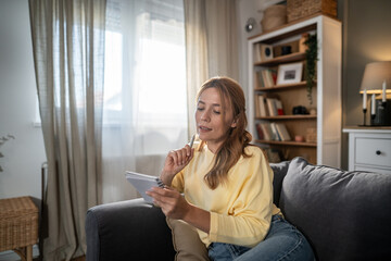 Woman thinking, writing notes in a living room