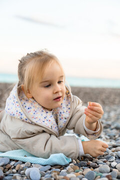 Little girl exploring shells on a pebble beach