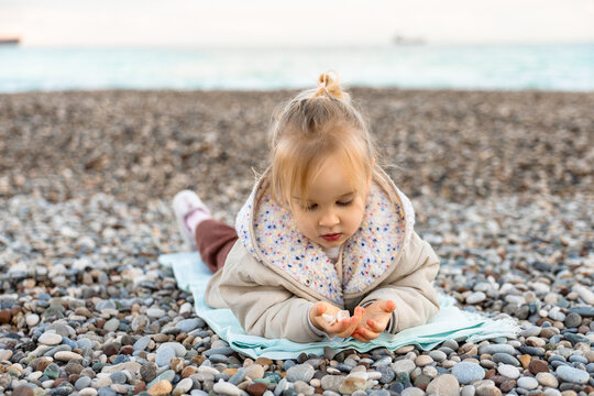Girl enjoying beach while examining shells