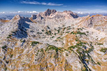 Aerial view showing rocky mountain Bobotov Kuk in Durmitor, Montenegro, with sparse green vegetation, winding hiking trails, and distant peaks