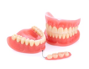 Obraz premium Set of false teeth including full dentures and a partial bridge, shown against white