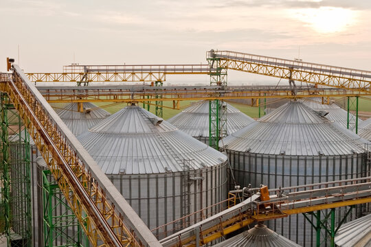Aerial view of industrial grain silos and conveyor bridges at sunset.