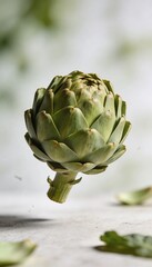 Obraz premium Fresh green artichoke floating in the air with scattered leaves on a light background