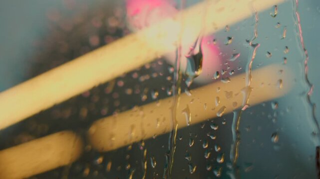 Raindrops on glass with city lights creating urban atmosphere
