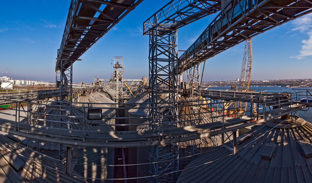 Industrial complex for grain processing with steel silos and conveyor systems.
