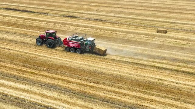 Red Tractor and Hay Baler Harvesting in Golden Field - Aerial View
