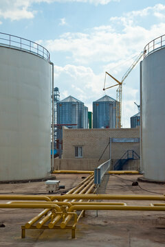 Industrial storage silos and yellow pipeline infrastructure at a manufacturing plant
