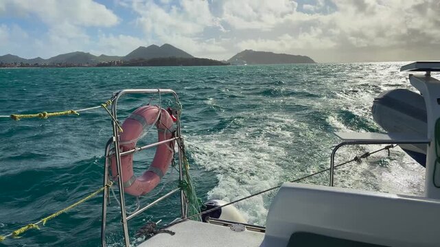 A boat trip in the Caribbean Sea near the island Saint Martin in the northeastern Caribbean. View of the island's rocky shores and ship's wake.
