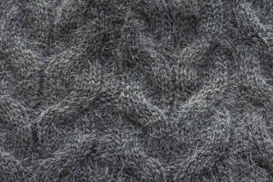 Grey knit fabric with pattern braids. Knitted seamless wool background, texture.  Grey cable knit cloth background.