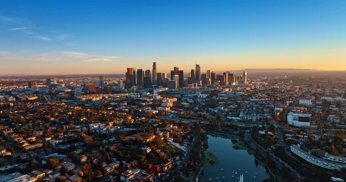 Flight over the scenery of green uptown of Los Angeles, California, USA. Approaching the high-rise downtown at sunset.