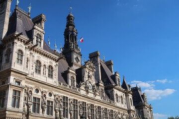 Obraz premium Détail du sommet de la façade de l’hôtel de ville / mairie de Paris, célèbre monument historique parisien, sur fond de ciel bleu (France)