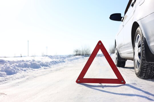 Warning triangle and broken car on roadside at snowy winter, space for text