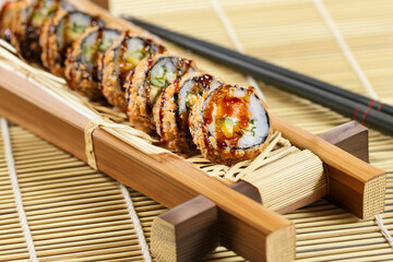 Crispy fried sushi roll with avocado and eel sauce Japanese crunchy sushi roll served on a bamboo tray Tempura sushi roll with avocado and cucumber filling © Mykhailo Feriukov