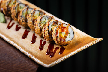 Crispy fried sushi roll with avocado and eel sauce Japanese crunchy sushi roll served on a bamboo tray Tempura sushi roll with avocado and cucumber filling © Mykhailo Feriukov