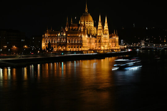 distant view of the Parliament building in Budapest, Hungary. River side night photo. brightly lit stone facade. neo-gothic style. old landmark. popular tourist attraction. travel and tourism