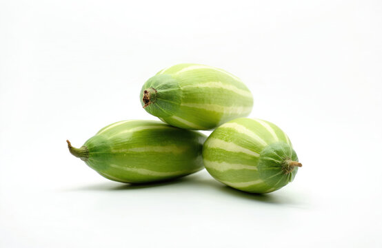 Three fresh green pointed gourds with white stripes stacked on white background. These vegetables are raw and healthy ingredients for Asian cuisine, ideal for healthy eating.