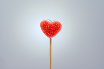 Heart-shaped gummy candy on a stick representing romance and sweet treats